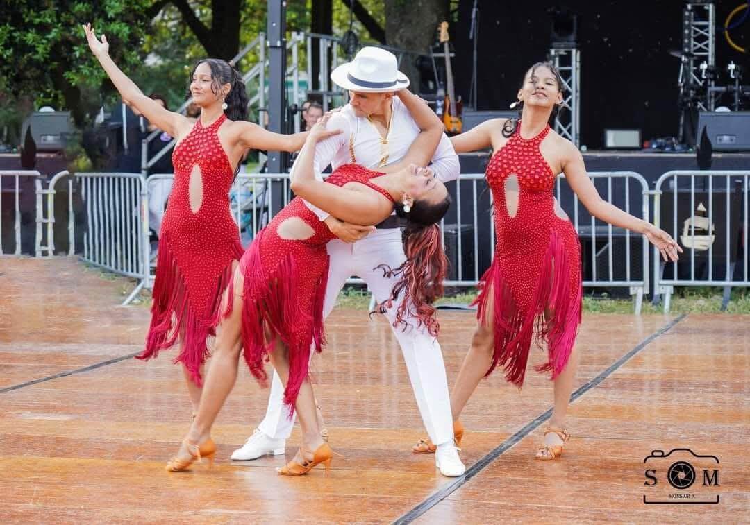 Trois danseuses en robe rouge et un homme en blanc